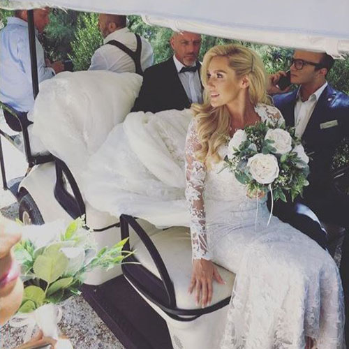 bride sitting in gold buggy holding white faux wedding flowers
