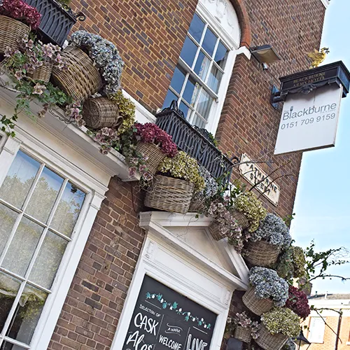pretty pastel faux floral installation for hotel and pub in wicker baskets over doorway