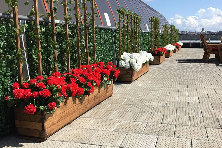 case study restaurant terrace with outdoor wooden planters, artificial hydrangeas and geraniums in red and white against faux ivy wall