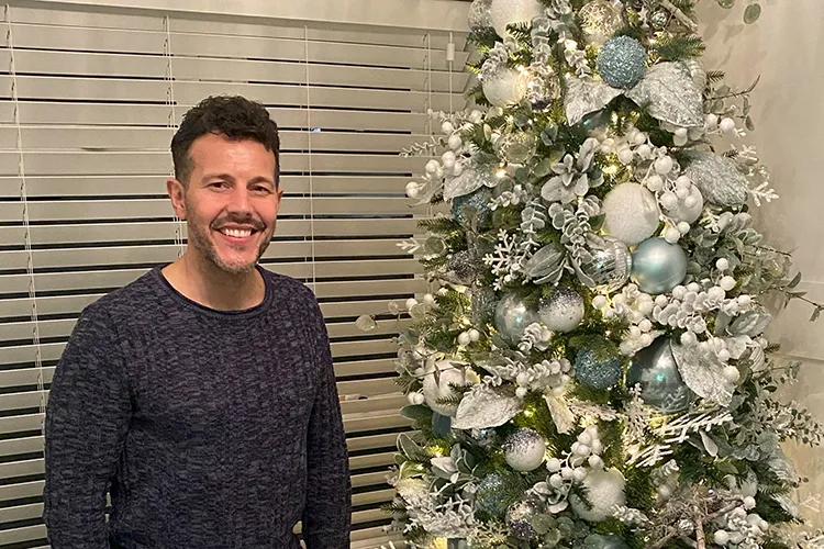 lee latchford-evans from Steps stood next to white and blue christmas tree