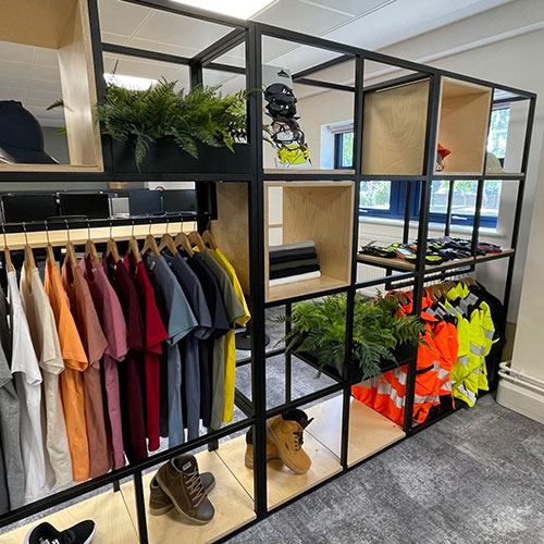 commercial artificial plants on shelves within a display unit with clothing and boots