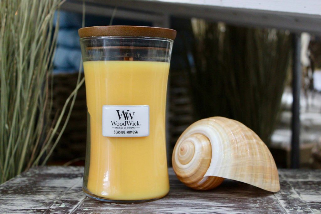 woodwick seaside mimosa candle next to shell