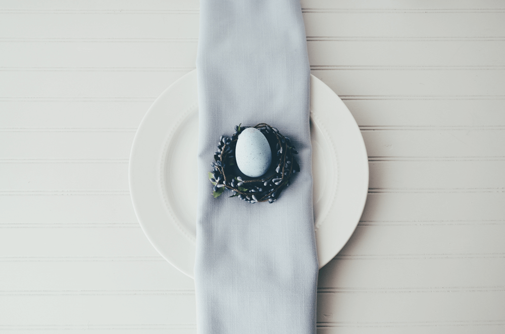Easter table setting ideas - egg in flower nest on napkin on plate - neutral tones