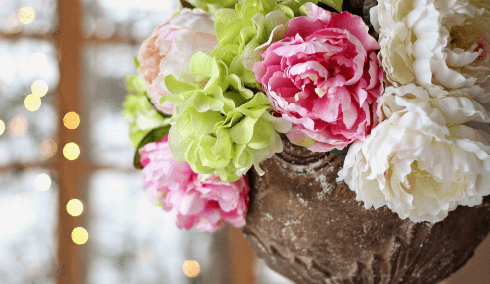 pink peonies green hydrangeas in stone flower pot summer wedding centrepiece