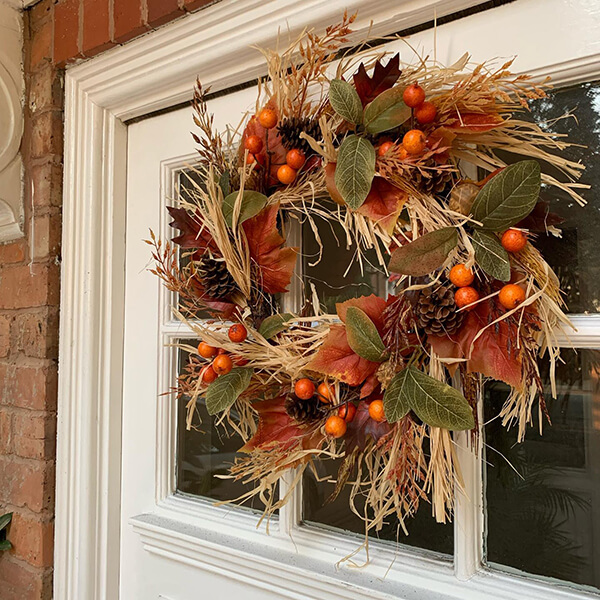 orange autumnal wreath deocration with grasses, pinecones and berries close up