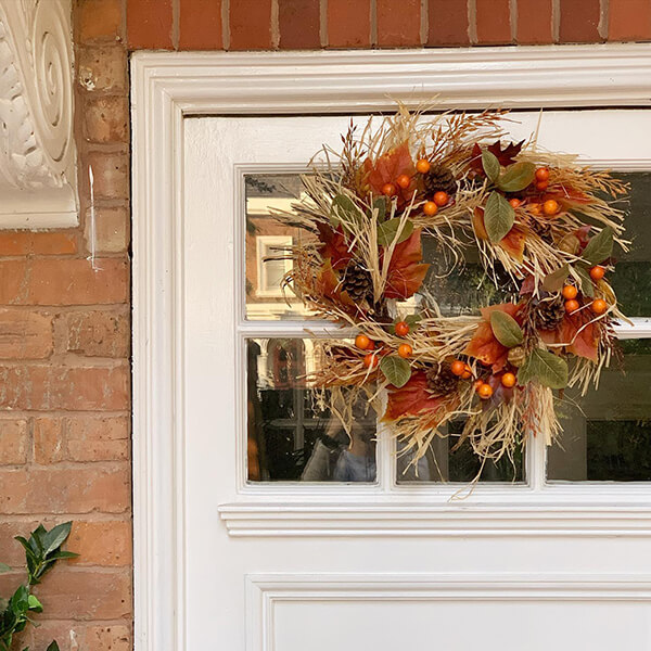 orange autumnal wreath deocration with grasses, pinecones and berries