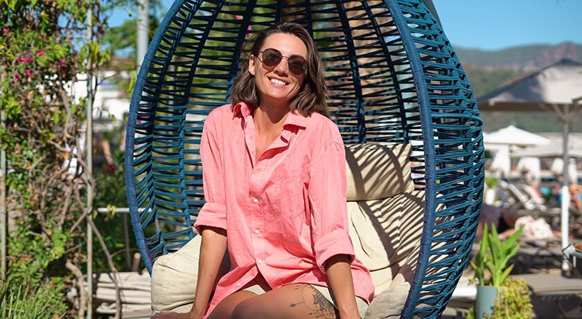 lady in pink shirt sitting in wicker egg chair outside