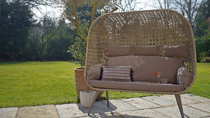 outdoor wicker egg chair sofa on patio in sunny garden