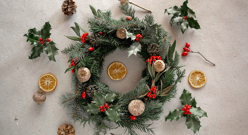 festive greenery wreath with pine, holly, poppy seed pods, orange slices