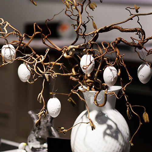 white hanging egg decorations on easter tree branches in white vase