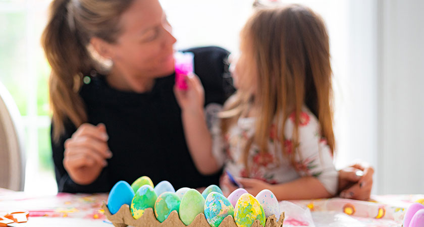 mother and child painting easter egg decorations for tree