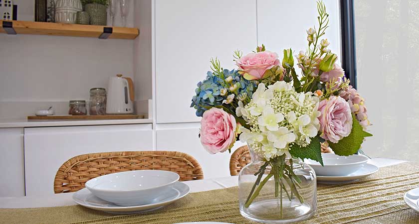 display of faux spring flowers on dining table with white crockery