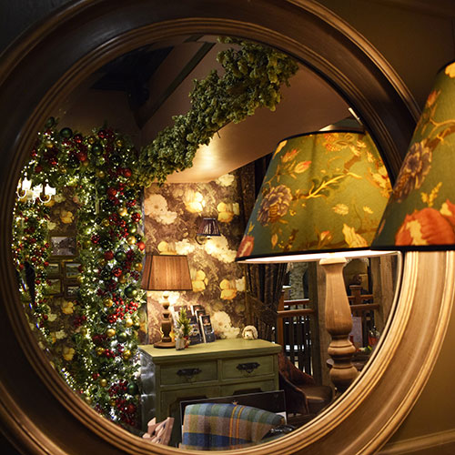 Reflection in round mirror of christmas decorations inside the inn