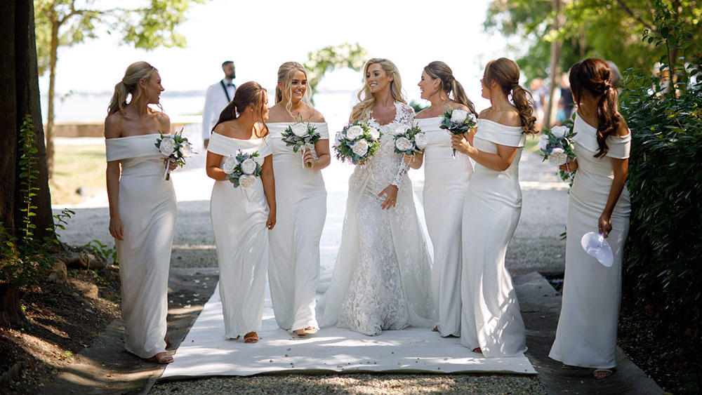 bride and six bridesmaids in white dresses with white artificial flower bouquets