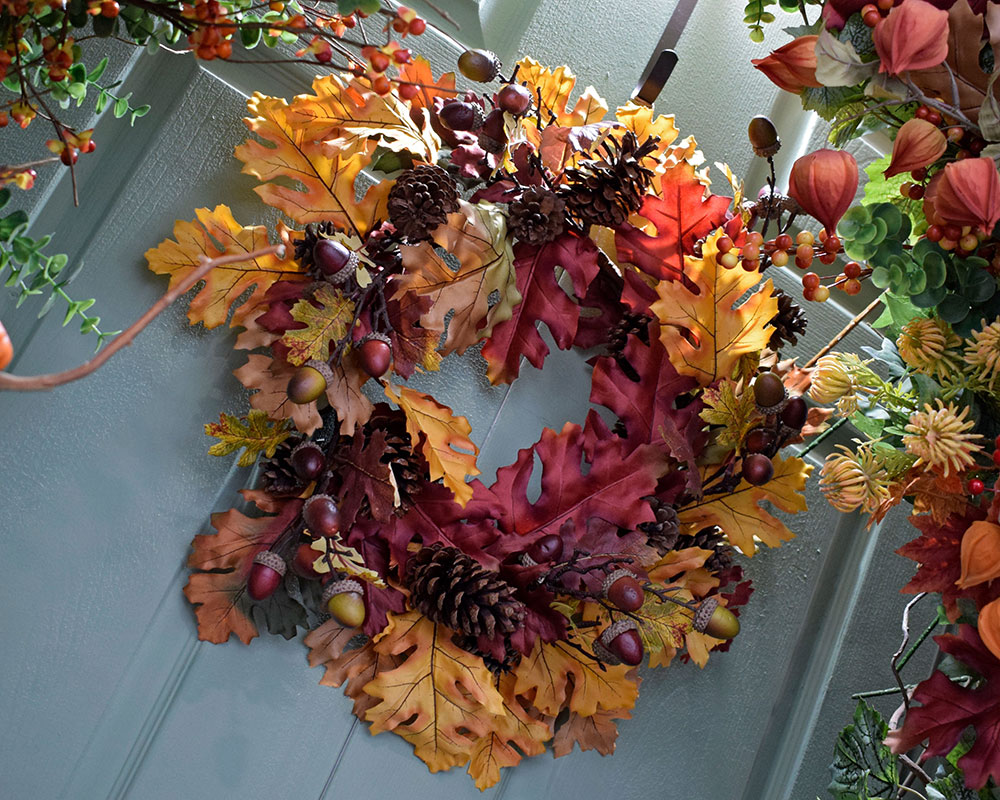 autumn decorating idea wreath with yellow, orange, red leaves and acorns and pinecones