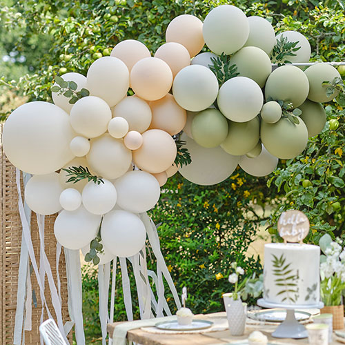 green, taupe and white baby shower balloon arch outside with foliage