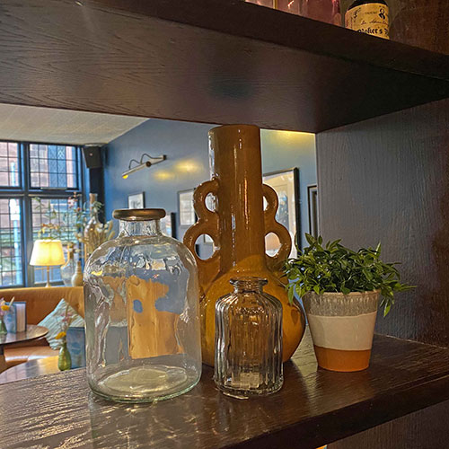 close up of dark wood shelving in bar with contemporary vases, pots and commercial fake plants