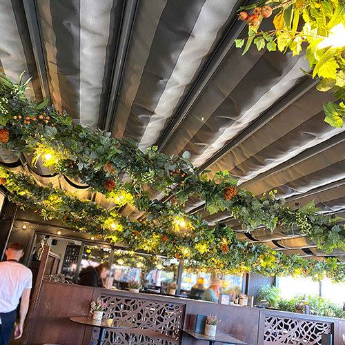 bar terrace outdoor commercial artificial plant installation with faux vines, flowers and lights