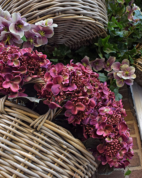 close up of artificial burgundy hydrangeas in wicker basket on pub wall