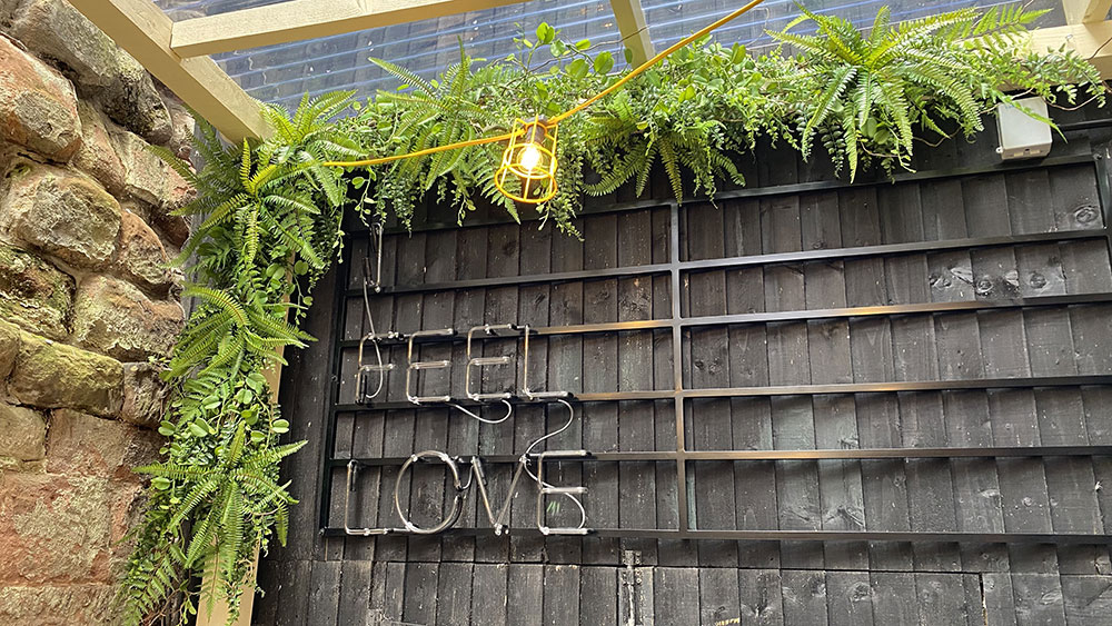 feel love light up sign on wooden fence with faux foliage display