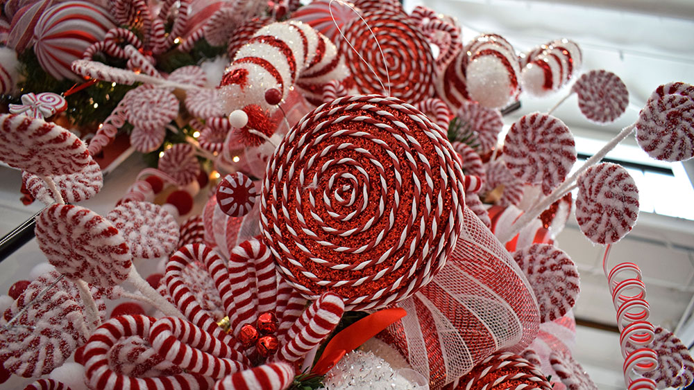 red and white swirl giant lollipop decoration amongst frosted candy cane themed christmas decorations