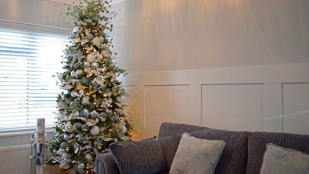 celebrity christmas decorating service - white and light blue christmas tree next to grey sofa