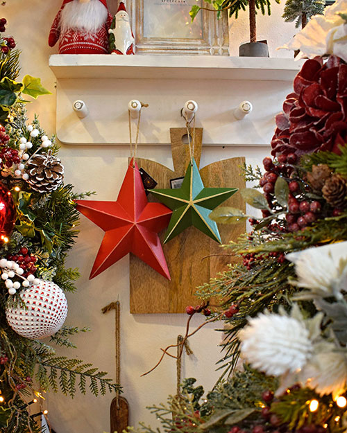 red and green hanging star decorations on hooks with wooden chopping board