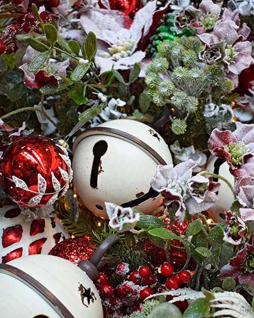 classic christmas decorations such as white bells, frosted red berries, mistletoe and festive artificial flowers
