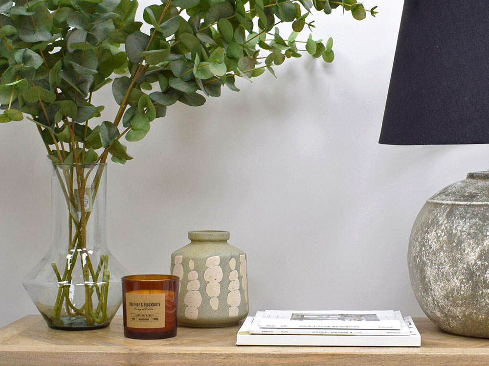 styling a console table with lamp, eucalyptus in vase, candles and accessories