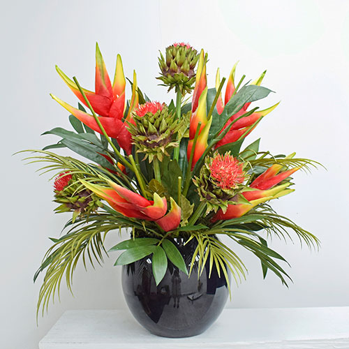 exotic red and green bespoke corporate artificial flowers in black vase on table