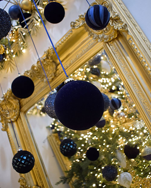 velvet navy blue baubles hanging in front of gold framed mirror
