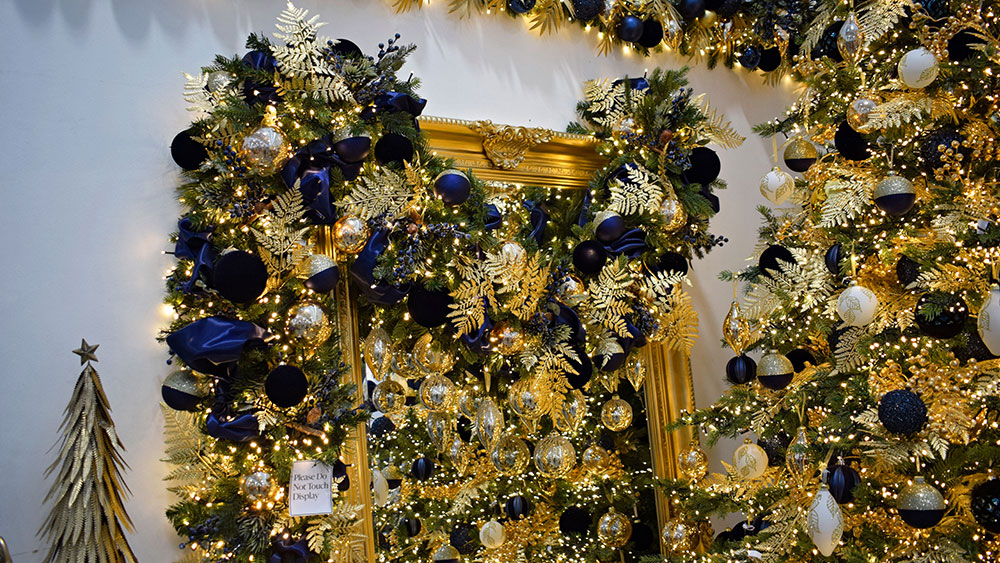 gold framed mirror draped with garland of gold and blue christmas decorations