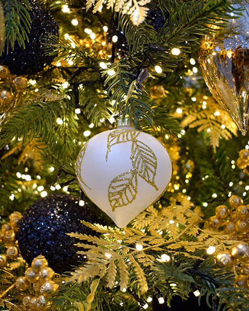 white bauble with gold leaf pattern on christmas tree