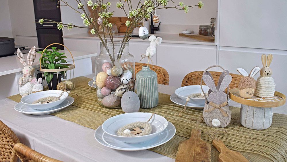 Neutral easter decorations on dining table with white crockery and vases with faux spring flowers