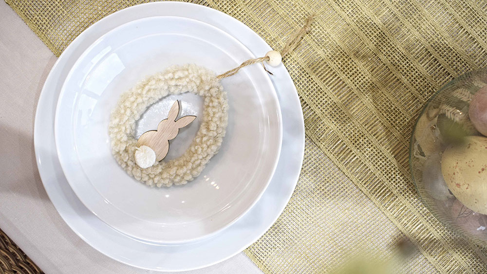 boucle fluffly neutral egg shaped hanging decoration with wooden bunny inside a white bowl on table