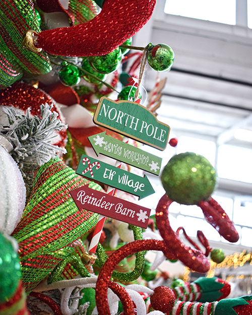 north pole sign with red and green elf christmas tree decorations