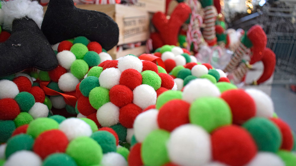 red, green, and white pom-pom baubles and elf feet in background