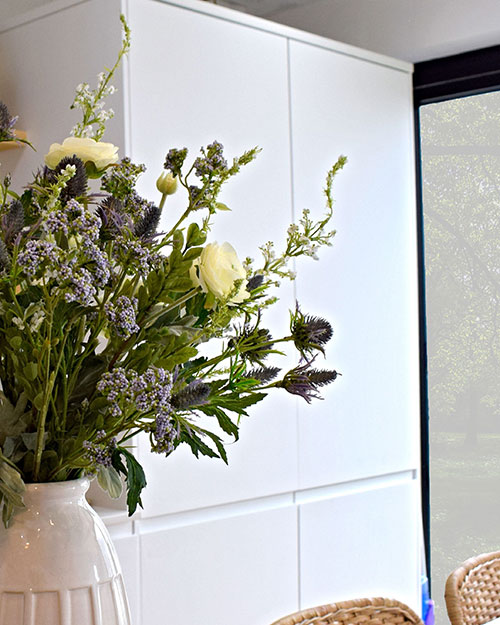 white, purple, blue, and lilac artificial flowers in white vase in kitchen