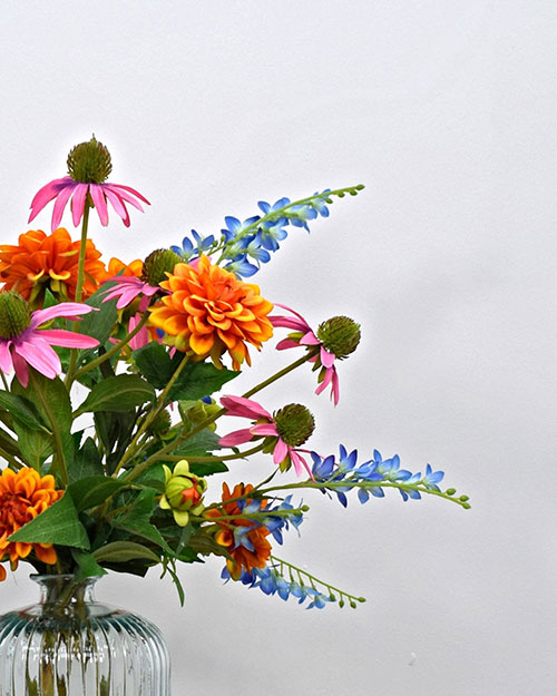 bright tropical pink, blue and orange artificial flowers in glass vase
