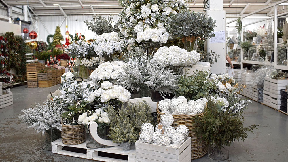 frosted christmas decorations, white baubles, icy faux foliage on display in crates, baskets, and vases