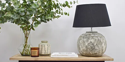 contemporary homeware supplies - artificial eucalyptus in glass vase, stoneware vase, candle, picture frame and lamp on side table