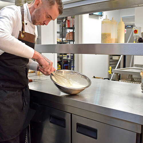 male chef whisking batter in bowl
