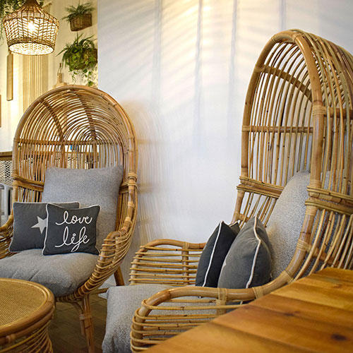 two rattan high back chairs with grey cushions inside leaf and vine coffee shop