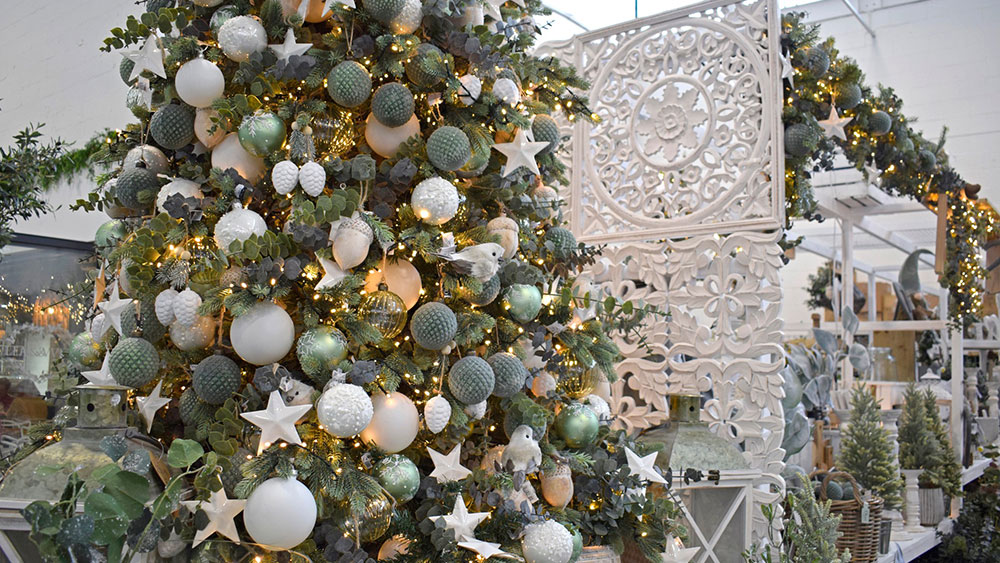 birds, stars, acorns, white and green christmas decorations on a tree with white carved panel behind