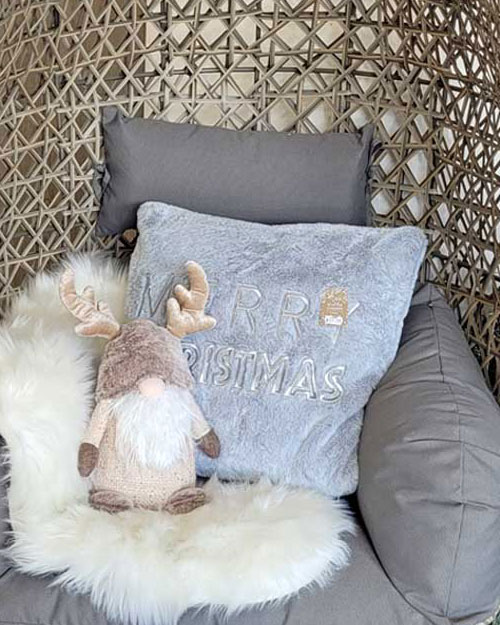 wicker chair with merry christmas cushion, faux fur and gonk in neutral colours