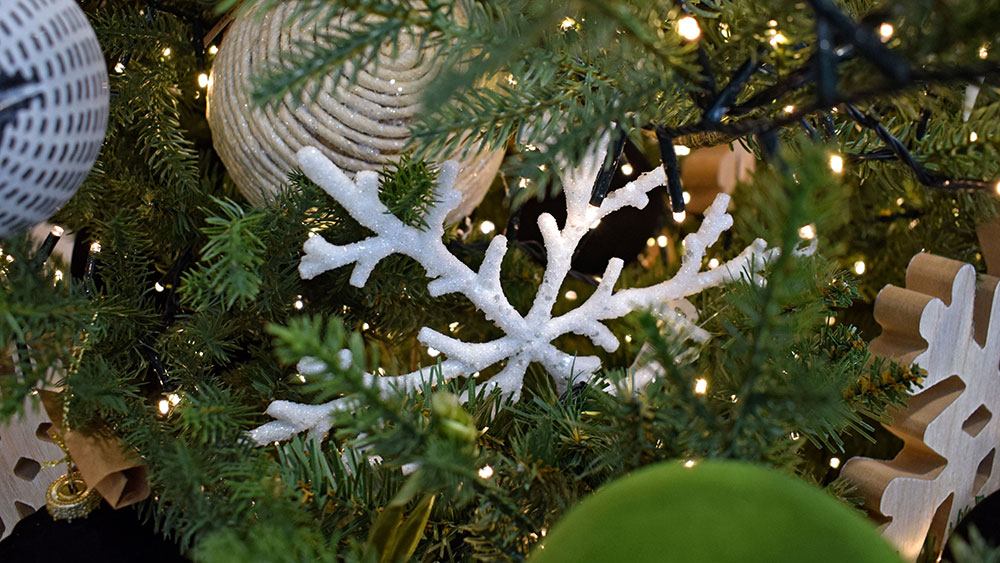 frosted white snowflake, wooden snowflake, white string bauble hanging in green Christmas tree