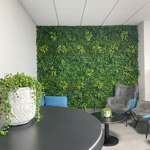 artificial green wall in office space with faux potted succulent plant and grey table and chairs