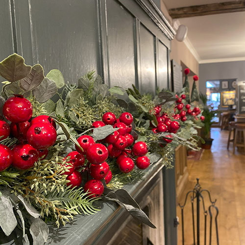 red berries and green foliage on manelpiece inside rake hall pub restaurant