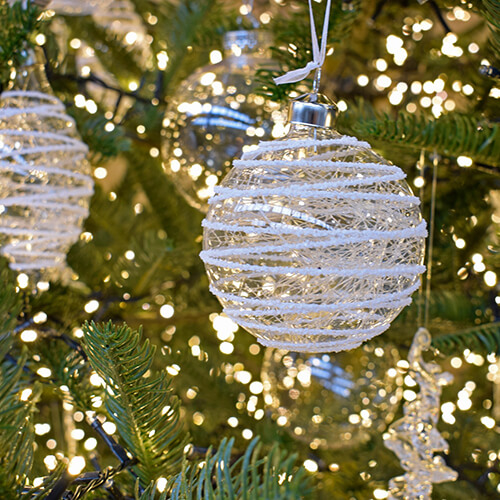clear glass baubles with white spiral pattern hanging on tree branch