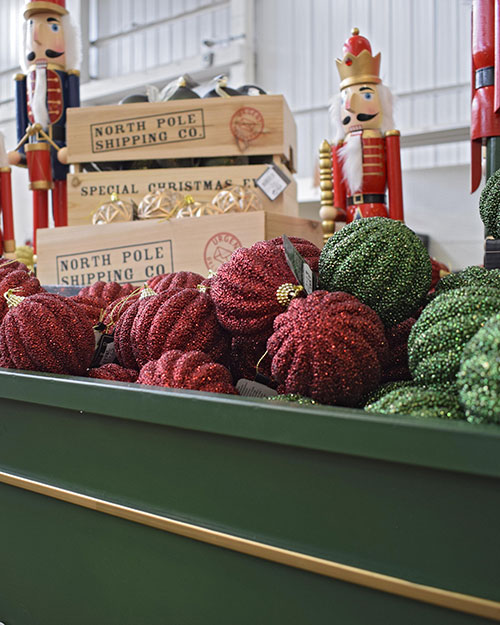 close up of green and red glitter baubles, north pole shipping co wooden crates and nutcracker figures